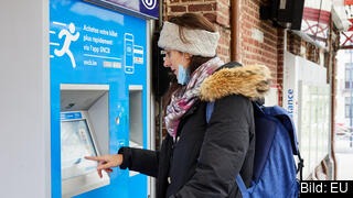 En kvinna köper en tågbiljett i en automat.